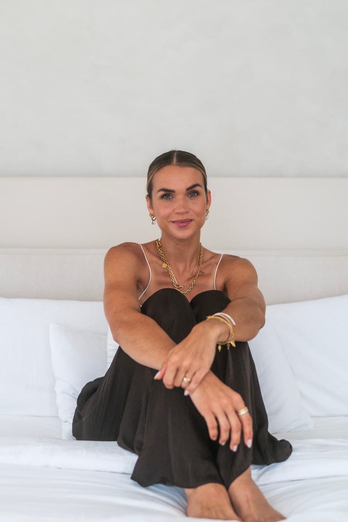 Anika sitzt frontal auf dem Bett und schaut ruhig in die Kamera