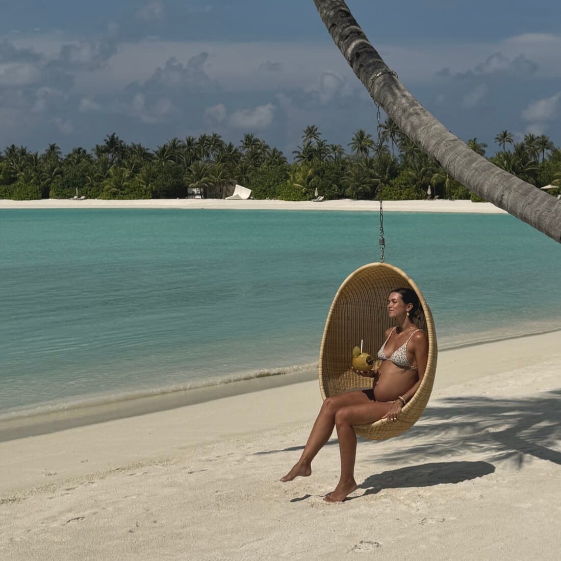 Anika in der Schaukel über dem Strand, das türkise Meer hinter ihr
